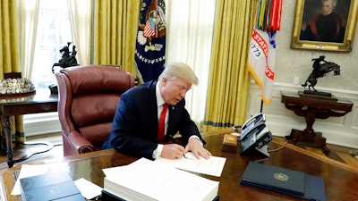 In this Dec. 22, 2017, file photo President Donald Trump signs into law a $1.5 trillion tax overhaul package in the Oval Office of the White House in Washington. New rules floated by the Trump administration lay out what kinds of businesses can take a 20 percent deduction against income taxes under the new tax law. With the proposed rules issued Wednesday, Aug. 8, 2018, the Treasury Department and the IRS had worked for six months to bring clarity to Congress' blueprint.