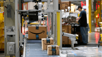 In this Aug. 3, 2017, file photo, packages pass through a scanner at an Amazon fulfillment center in Baltimore. Amazon is paying workers to defend the company on Twitter, reassuring critics that they make enough money to live and are allowed to take bathroom breaks. The tweets are part of Amazon’s plan to combat negative headlines and online chatter about poor working conditions at its warehouses.