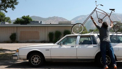 In this Tuesday, Aug. 7, 2018 photo, Mark Johnson unloads his homemade contraptions known as 'The Mastodon' at the Ogden Bicycle Collective in Ogden, Utah. The contraption is just the latest homemade set of wheels that he has built for UpCycle: Bikes and Boards. Johnson plans to start a business taking old bikes and scraps and rebuilding them into rideable pieces of art.