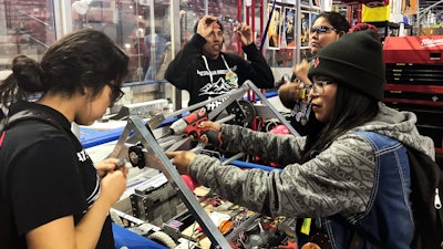 This March 3, 2018 photo provided by Heather Anderson shows, from left, Navajo Mountain High School students Nahida Smith, Myra King and Breana Bitsinne compete in a Utah regional robotics competition in West Valley City, Utah. The team from a remote town in southern Utah is now headed to an international robotics competition Aug. 14 in Mexico City, Mexico. They were invited to compete in the First Global Challenge, which will draw teams from 190 countries to create robots capable of feeding power plants and building environmentally efficient transmission networks.