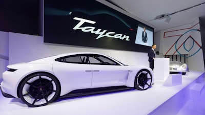 In this Aug. 6, 2018, photo provided by Porsche AG, Oliver Blume, CEO of Porsche AG, speaks next to the Taycan during the ceremonial opening of “70 Years Porsche Sportscar” at the Porsche Museum in Stuttgart, Germany. While Tesla grapples with internal issues like production delays, a sometimes-erratic CEO and a recent about-face on whether to go private, its rivals are moving aggressively into the luxury electric vehicle space. Porsche is taking on Tesla's Model S high performance luxury car with the Taycan, expected to reach the market in late 2019.