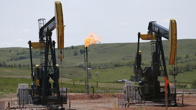 In this June 12, 2014 file photo, natural gas is burned off near pumps in Watford City, N.D. As Trump rolls back some Obama-era rules on climate-changing methane pollution, Colorado officials say their regulations have reduced oil field leaks. A report released Thursday, Aug. 23, 2018, shows required state inspections helped find and repair 73,000 methane leaks over three years.