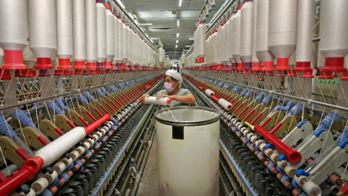 In this photo a worker prepares to load a cotton thread barrel into the machine at a textile factory in Huaibei in central China's Anhui province.