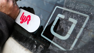 In this Jan. 31, 2018, file photo, a Lyft logo is installed on a Lyft driver's car next to an Uber sticker in Pittsburgh. The “gig” economy might not be the new frontier for America’s workforce after all. From Uber to Lyft to TaskRabbit to YourMechanic, so-called gig work has been widely seen as ideally suited for people who want the flexibility and independence that traditional jobs don’t offer. Yet the evidence is growing that over time, they don’t deliver the financial returns many expect.