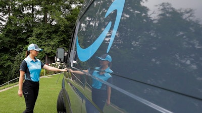 In this June 27, 2018, file photo, Parisa Sadrzadeh, a senior manager of logistics for Amazon.com, opens the door of an Amazon-branded delivery van at the request of a photographer in Seattle, following a media event for Amazon to announce a new program that lets entrepreneurs around the country launch businesses that deliver Amazon packages. Amazon says it has ordered 20,000 vans for its new delivery program. The online retailer says “tens of thousands” of individuals have applied for the program, and it had to up its van order to 20,000 from 4,500.
