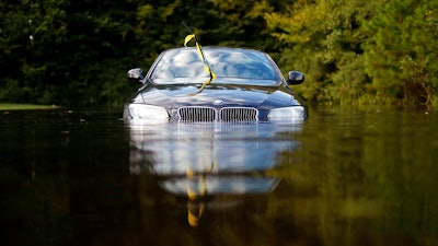 In this Tuesday, Sept. 18, 2018, file photo a car sits in a flooded parking lot at an apartment complex near the Cape Fear River as it continues to rise in the aftermath of Hurricane Florence in Fayetteville, N.C. As flooding continues in the Carolinas after Florence’s massive rainfall, experts say high water will damage thousands of vehicles.