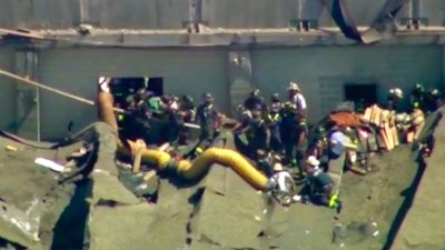 This aerial frame grab from video by WFLD-TV in Chicago shows rescue personnel at the scene where several people were reported trapped inside a Chicago water reclamation plant after a fire and possible explosion caused part of the building's roof to collapse Thursday, Aug. 30, 2018.