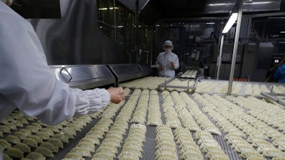 In this July 18, 2018, photo, workers inspect dumplings on a conveyor belt that are made at an automated factory of CJ CheilJedang Corp. in Incheon, South Korea. South Korea’s largest food company is making a multimillion-dollar bet on “mandu,” developing its own machines to automate the normally labor-intensive production of the Korean dumpling and building factories around the world.