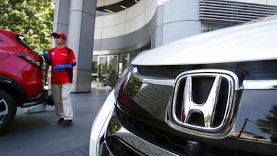 In this July 31, 2018, file photo, an employee of Honda Motor Co. cleans a Honda car displayed at its headquarters in Tokyo. Honda is recalling about 232,000 2018 Accord vehicles and 2019 Insight hybrid cars in the U.S. for malfunctioning software for the rear camera display. Honda said Friday, Sept. 28, 2018, that there have been no reports of accidents or injuries related to the problem.