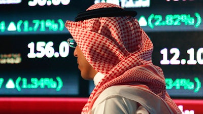 In this June 15, 2015, file photo, a Saudi man walks through the Tadawul Saudi Stock Exchange in Riyadh, Saudi Arabia. Saudi Arabia's sovereign wealth fund invested over $1 billion on Monday, Sept. 17, 2018, in an American electric car manufacturer just weeks after Tesla CEO Elon Musk earlier claimed the kingdom would help his own firm go private.