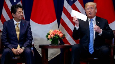 President Donald Trump takes a letter from North Korean leader Kim Jong-un from his suit coat pocket during a meeting with Japanese Prime Minister Shinzo Abe at the Lotte New York Palace hotel during the United Nations General Assembly, Wednesday, Sept. 26, 2018, in New York.