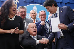 State Sen. Kevin de Leon, D-Los Angeles, second from right, displays his environmental measure SB100 after is was signed into law by Calif., Gov. Jerry Brown front center, Monday, Sept. 10, 2018, in Sacramento, Calif. Brown, surrounded by lawmakers and activists including Assembly members Lorena Gonzalez Fletcher, of San Diego, second from left, Ken Cooley, of Rancho Cordova, third from left and billionaire activist Tom Steyer, right, signed SB100 which sets a goal of phasing out all fossil fuels from the state's electricity sector by 2045.