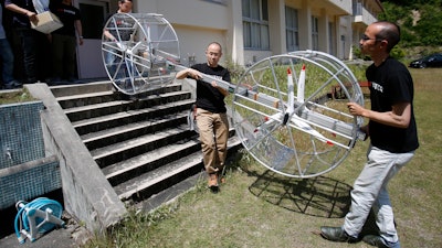 In this June 3, 2017, file photo, members of Cartivator carry propellers of the test model flying car in Toyota, central Japan. The Japanese government has started a “flying car” project, bringing together more than a dozen companies, including All Nippon Airways, electronics company NEC, Toyota-backed startup Cartivator and Uber, the ride-hailing service. Toyota and its group companies have also invested 42.5 million yen ($375,000) in a Japanese startup, Cartivator, that is working on a flying car.