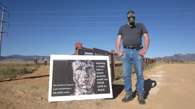 Stephen Parlato wears a gas mask next to his sign warning about the dangers of plutonium at Rocky Flats National Wildlife Refuge outside Denver on Saturday, Sept. 15, 2018, the first day the refuge was open to the public. The refuge is on the outskirts of a former U.S. government factory that manufactured plutonium triggers for nuclear weapons.