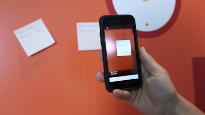 Hector Minto, a Senior Technology accessibility evangelist at Microsoft, demonstrates an app that can audibly describe a handwritten note during an interview with The Associated Press, at Microsoft offices in London, Friday, July 27, 2018. Improvements in artificial intelligence, combined with the decreasing cost of hardware, are making it possible for inventors to develop new products without the need for the deep pockets of governments or big corporations. With the help of 3D printers and the increased processing power of home computers, they are creating devices designed for people with motor, vision, hearing and cognitive impairments.