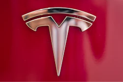 This Aug. 8, 2018, file photo shows a Tesla emblem on the back end of a Model S in the Tesla showroom in Santa Monica, Calif. Tesla is dropping two of the seven standard colors it had offered to customers to streamline production. In a tweet early Tuesday, Sept. 11, CEO Elon Musk said obsidian black and metallic silver will still be available, but at a higher cost. Tesla fans can still get solid black and “midnight silver metallic,” as well as pearl white, deep blue metallic and red as standard color choices.