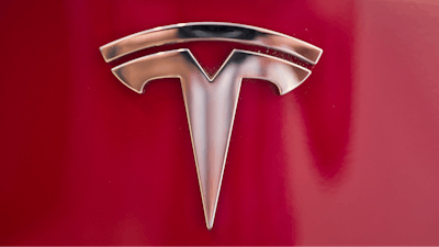 This Aug. 8, 2018, file photo shows a Tesla emblem on the back end of a Model S in the Tesla showroom in Santa Monica, Calif. Tesla is dropping two of the seven standard colors it had offered to customers to streamline production. In a tweet early Tuesday, Sept. 11, CEO Elon Musk said obsidian black and metallic silver will still be available, but at a higher cost. Tesla fans can still get solid black and “midnight silver metallic,” as well as pearl white, deep blue metallic and red as standard color choices.