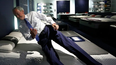 In this June 26, 2018, photo City Furniture CEO Keith Koenig, jumps onto a waterbed as he speaks during an interview with the Associated Press, in Tamarac, Fla. Koenig and inventor Charles Hall, pioneers of the waterbed industry in the United States, are hoping to generate a new wave of popularity for the old furniture concept by using a wholesome new pitch.