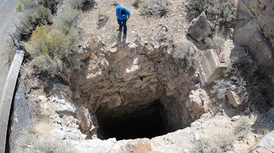 This Sept. 7, 2018, photo shows Nick Castleton looking down a shaft, near Eureka, Utah. Underneath the landscape of the U.S. West lie hundreds of thousands of abandoned mines, an underground world that can hold serious danger and unexpected wonder.