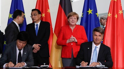 In this July 9, 2018 file photo German Chancellor Angela Merkel, second from right, and Chinese Premier Li Keqiang, third from left, attend a contracts signing ceremony between German car maker BMW CEO Harald Krueger, right, and Qi Yumin CEO of the Brilliance Group, left front, during a meeting in the chancellery in Berlin. German automaker BMW said Thursday, Oct. 11, 2018 it is taking a majority stake in its China joint venture and investing 3 billion euros in future production there as it prepares to meet increased demand for electric vehicles.