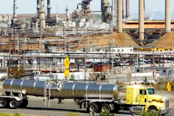 This March 9, 2010, file photo shows a tanker truck passing the Chevron oil refinery in Richmond, Calif. Federal officials say Chevron Corp. has agreed to pay a nearly $3 million fine and spend $160 million on environmental improvements and upgrading oil refineries to resolve allegations the company violated pollution laws. The U.S. Department of Justice announced the agreement Wednesday, Oct. 24, 2018.