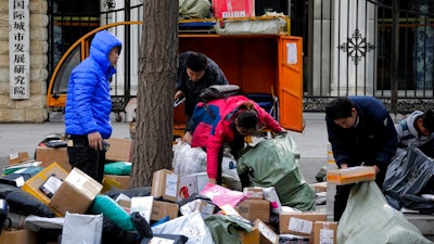 In this Tuesday, Oct. 30, 2018, photo, delivery workers sort boxes of goods for their customers outside the capital city development academy in Beijing. An official measure of China's manufacturing activity fell to a two-year low in October, adding to pressure on Beijing to shore up economic growth amid a tariff war with Washington. The monthly purchasing managers' index issued Tuesday by the National Bureau of Statistics and an industry group, the China of Logistics and Purchasing, fell to 50.2 from September's 50.8 on a 100-point scale.