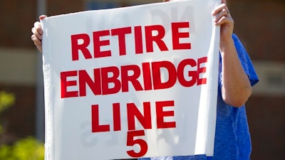 In this July 6, 2017, file photo, Lauren Sargent, takes part in a protest before the Enbridge Line 5 pipeline public information session in Holt, Mich. Officials tell The Associated Press that Michigan Gov. Rick Snyder's administration and Canadian pipeline giant Enbridge have reached a deal on replacing 65-year-old twin pipelines in a channel linking two of the Great Lakes. An announcement was scheduled for Wednesday Oct. 3, 2018. Officials tell the AP the agreement calls for shutting down the Line 5 pipes in the Straits of Mackinac connecting Lakes Huron and Michigan.