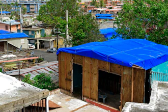 In this Oct. 19, 2017, file photo, homes in the Cantera area are covered with FEMA tarps, where buildings from the Hato Rey area stand in the background in San Juan, Puerto Rico. A new law requires the Federal Emergency Management Agency to investigate how it came to award Hurricane Maria relief contracts to a company with an unproven record. The Associated Press reported last year that the newly-formed contractor, Florida-based Bronze Star, LLC, won more than $30 million in FEMA contracts but never delivered the emergency tarps and plastic sheeting for repairs of damaged homes in Puerto Rico.