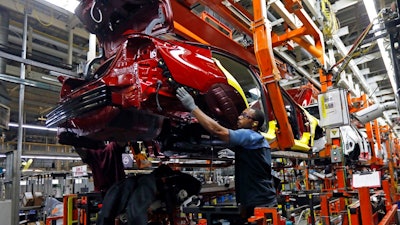 In this Sept. 27, 2018, file photo line technicians work on assembling a redesigned Nissan Altima sedan at its Nissan Canton Vehicle Assembly Plant in Canton, Miss. On Tuesday, Oct. 16, the Federal Reserve reports on U.S. industrial production for September.