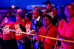 Protesters stand behind police tape, watching as police and first responders tend to the scene after a truck collided with into protesters calling for the right to form unions Tuesday, Oct. 2, 2018, in Flint, Mich. Police said the collision appears to be an accident.