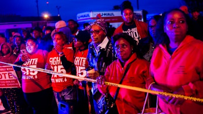 Protesters stand behind police tape, watching as police and first responders tend to the scene after a truck collided with into protesters calling for the right to form unions Tuesday, Oct. 2, 2018, in Flint, Mich. Police said the collision appears to be an accident.