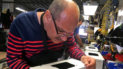 Former Iraqi refugee Majid Al Lessa works on a lighting fixture on the assembly floor of LiteLab, which employs refugees, Friday, Sept. 28, 2018, in Buffalo, N.Y. Thousands of refugees have settled in Buffalo in recent years even as others have left the city. Some locals worry that the Trump administration's policies reducing the numbers of new arrivals will harm the city's economy.