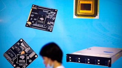 In this May 18, 2018, photo, a visitor walks past a display showing microchips and circuit boards at the 21st China Beijing International High-tech Expo in Beijing. The Trump administration imposed restrictions on technology exports to a Chinese semiconductor maker on Monday, Oct. 29, 2018, citing national security grounds amid a mounting tariff battle with Beijing.