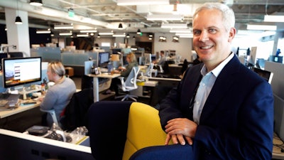 In this Tuesday, Oct. 2, 2018, photo Urban Airship product and engineering executive Mike Herrick works at his desk with photos of his daughter, Lauren, and wife Erin at his side in Portland, Ore. The tensions between the pride Herrick takes in his profession and his parental qualms about technology tug particularly hard when he sees his daughter, Lauren, and her friends texting each other instead of talking when they're sitting 5 feet apart.