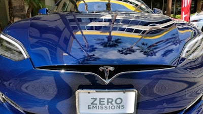 In this Oct. 24, 2016, file photo, palm trees are reflected on the hood of a Tesla Model S on display in downtown Los Angeles. Tesla says it recorded one accident for every 3.34 million miles driven when the autopilot was engaged. That number of per-mile accidents rises to 1.92 million when autopilot is not on.