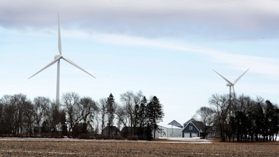 In this Feb. 2, 2018 file photo, wind turbines stand over a farmhouse near Northwood, Iowa. A new study out of Harvard finds that ramping up wind power in America would also dial up the nation’s temperatures.