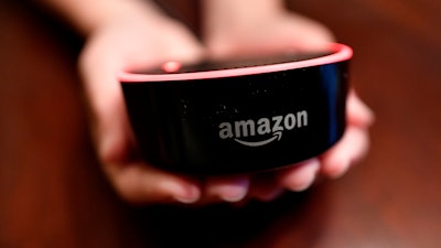 In this Aug. 16, 2018, file photo a child holds his Amazon Echo Dot in Kennesaw, Ga. Amazon.com Inc. reports earnings Thursday, Oct. 25.