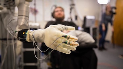 Nathan Copeland, who was paralyzed from the chest down in a car accident, controls a prosthetic arm and hand at the University of Pittsburgh Medical Center.