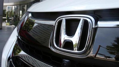 In this July 31, 2018, file photo, an employee of Honda Motor Co. cleans a Honda car displayed at its headquarters in Tokyo. Japanese automaker Honda Motor Co. is reporting Tuesday, Oct. 30, 2018, a 21 percent jump in fiscal second quarter profit on cost cuts and healthy motorcycle sales.