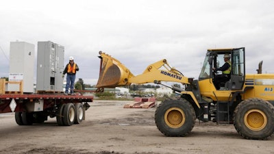 In this Friday, Oct. 12, 2018 photo, Andy Thomas, left, directs Ben Thomas as they unload electrical equipment for Independent Barley & Malt on the 44-acre site of Michigan Hub, Inc. clean power-generating facility, in Litchfield, Mich.