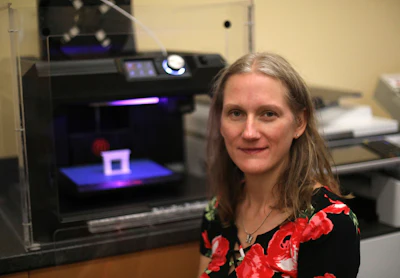 In this Sept. 19, 2018, photo, Patty Krncevic sits next to the 3D printer that she used at the Oregon Branch Library to make part of a cast replica that has a footprint of her stillborn daughter on it, in Oregon, Ohio. For Krncevic, the printer was instrumental in creating her organization, Footsteps 4 Little Angels.