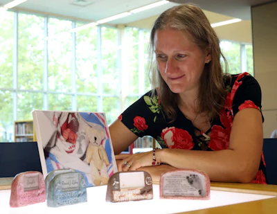 In this Sept. 19, 2018, photo, Patty Krncevic sits next to the cast replica footprint of her recently stillborn daughter that she created with the Oregon Branch Library's 3D printer, in Toledo, Ohio. A picture of her daughter's feet next to a little bear that she got from the hospital is with the replicas.