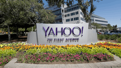 In this July 19, 2016, file photo, flowers bloom in front of a Yahoo sign at the company's headquarters in Sunnyvale, Calif. Yahoo has agreed to pay $50 million in damages and provide two years of free credit-monitoring services to about 200 million people in the U.S. and Israel whose email addresses and other personal information were stolen as part of the biggest security breach in history.