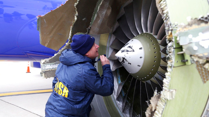 In this April 17, 2018, file photo, a National Transportation Safety Board investigator examines damage to the engine of the Southwest Airlines plane that made an emergency landing at Philadelphia International Airport in Philadelphia. In new accounts released Wednesday, Nov. 14, into the April accident, the flight attendants described being unable to bring the woman back in the plane until two male passengers stepped in to help. The flight attendants told investigators at least one of the men put his arm out of the window and wrapped it around the woman’s shoulder to help pull her back in.