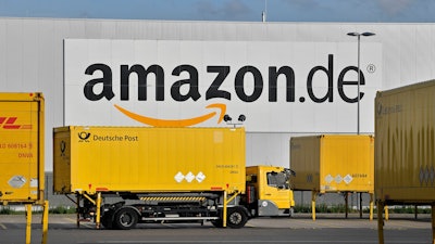 In this file photo dated Wednesday, Nov. 14, 2018, post trucks leaves the Amazon Logistic Center in Rheinberg, Germany. Germany's antitrust agency said Thursday Nov. 29, 2018, it has begun an investigation into online retailer Amazon over complaints that it's abusing its dominant position to the detriment of other sellers using its platform.