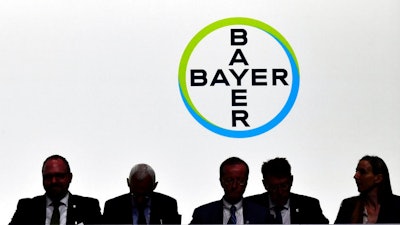 In this May 25, 2018 file photo members of the supervisory board sit in front of the company logo during the annual shareholders meeting of German chemical giant Bayer AG in Bonn, Germany. Bayer said Thursday, Nov 29, 2018 it will cut 12 000 jobs, most of them in Germany.