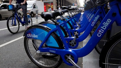 In this July 22, 2014, file photo parked Citi Bikes line a street in New York. Ride-share companies are capitalizing on voter enthusiasm ahead of Tuesday’s midterm elections by offering free or discounted rides to the polls in shared cars or on bikes. Bike share company Motivate, which operates Citi Bike, is offering free bike rides.
