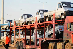 In this Oct. 31, 2018, photo, a staff members walks past a semi truck loaded with new vehicles in the parking lot for a local automaker in Qingdao in eastern China's Shandong province. China's auto sales sank for a fourth month in October, tumbling 13 percent from a year earlier and adding to an unexpectedly painful downturn for global automakers in their biggest market.