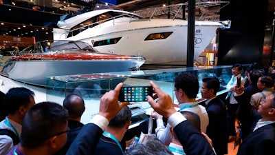 In this Nov. 6, 2018, photo, visitors gather around an Italian Yacht displayed at the China International Import Expo in Shanghai. Visitors to the vast trade fair meant to rebrand China as a welcoming import market could sip Moroccan wine, ogle Italian yachts and watch a Japanese industrial robot play ping-pong.