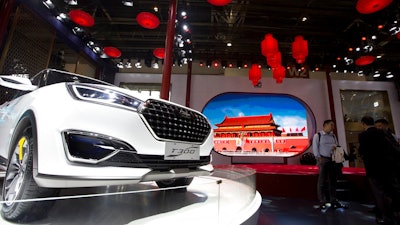 In this file photo taken Monday, April 25, 2016, visitors to Auto China 2016 stand near Zotye Auto's T300 SUV displayed in Beijing, China. Chinese automaker Zotye Auto says it plans to start selling vehicles in the United States in 2020.